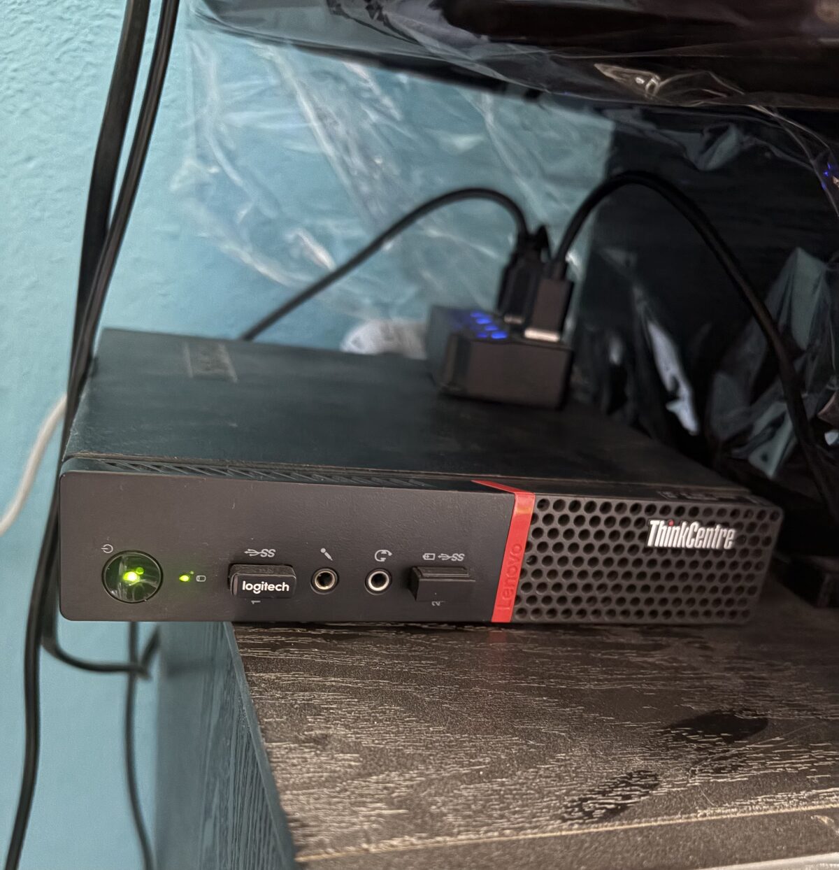Una mini PC Lenovo ThinkCentre encendida bajo el mostrador de un negocio